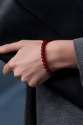 Hand wearing a red amber bracelet with a dark background