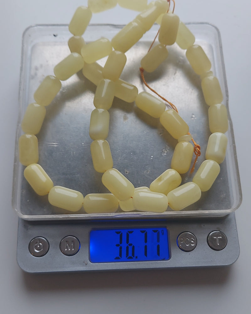 Beyaz kehribar tesbih hassas terazide tartılıyor, ekranda 36,77 gram yazıyor